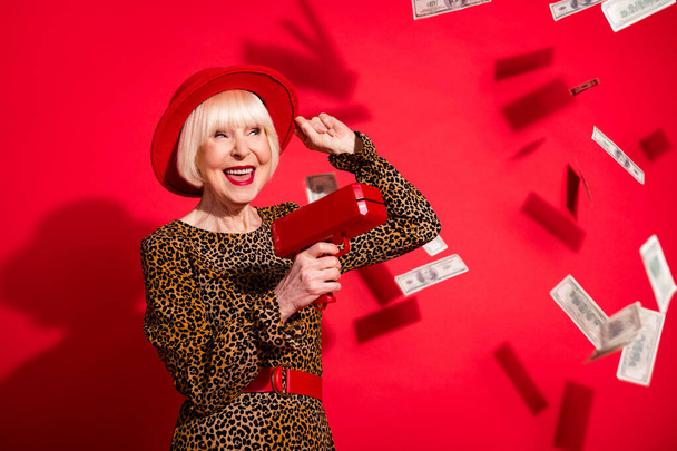 Photo of cheerful aged woman happy positive smile waste money rich dollars cash air fly isolated over red color background - Foto, Imagem