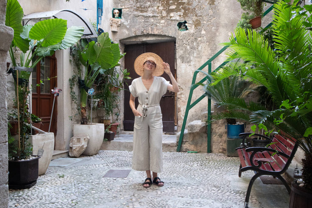 Belle jeune voyageuse blonde portant un chapeau de soleil en paille et profitant de vacances d'été dans une vieille ville côtière traditionnelle au coût de l'Adriatique, Croatie - Photo, image