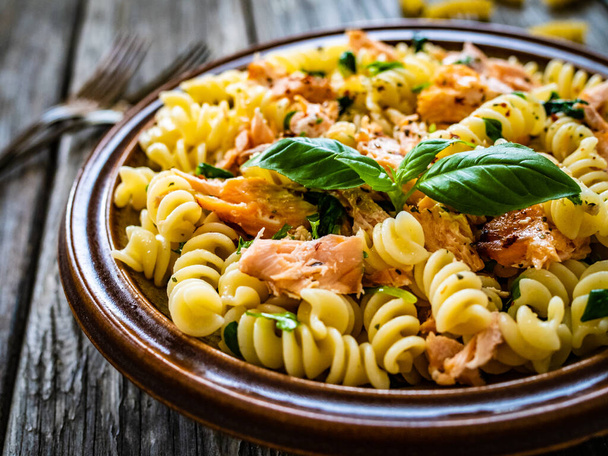 Fusilli with roasted salmon on wooden table  - Foto, imagen