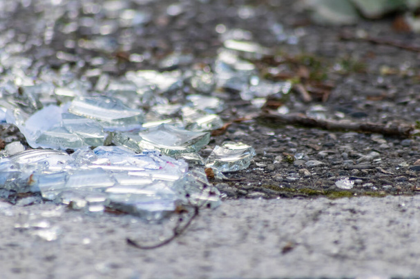 Острые осколки разбитой стеклянной бутылки на земле с острыми лезвиями опасны от вандализма и пьяных людей, показывающих хрупкую бутылку и разбитые напитки, раздавленные в качестве отходов переработки оружия - Фото, изображение