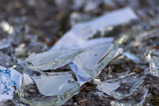 Sharp shards of a broken glass bottle on the ground with sharp blades are dangerous from vandalism and drunk people showing fragile bottle and smashed beverage crushed as weapon recycling waste - Photo, Image