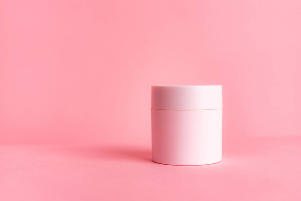 Pink jar with cream on a pink background . Cosmetology. Skin care. Article about the choice of cream. Article about the choice of care cosmetics. Spa treatments. Copy space - Фото, изображение