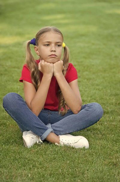 Little girl cute ponytails hairstyle relaxing on green grass, sad day concept - Foto, immagini