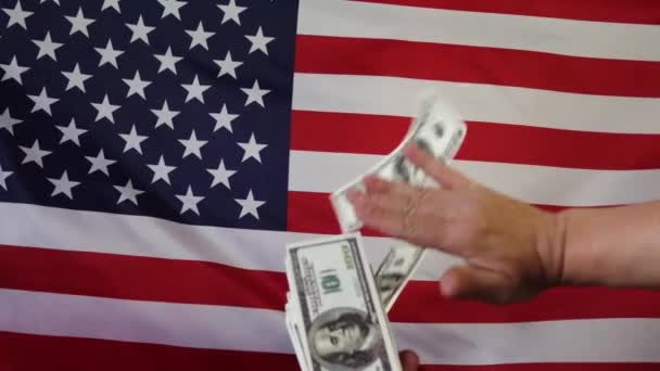 Dollari in caduta sullo sfondo della bandiera americana.In slow motion. Pioggia di soldi. - Filmati, video