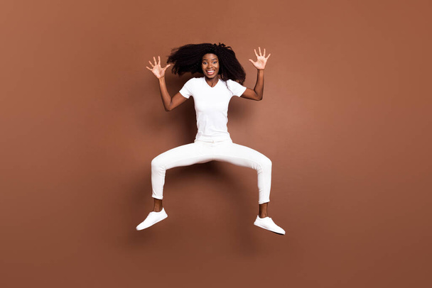 Full body photo of young excited black girl happy positive smile jump up isolated over brown color background - Fotó, kép