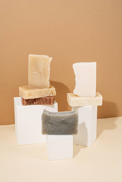 különböző kézzel készített szappanok összetétele fehér pódiumokon krém háttér - Fotó, kép