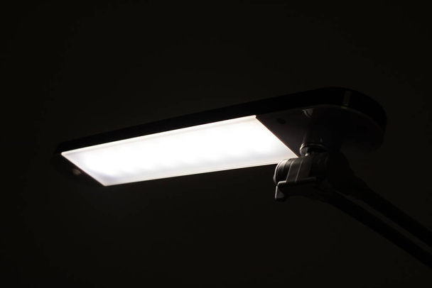 Table fluorescent lamp shines in the dark - Photo, Image