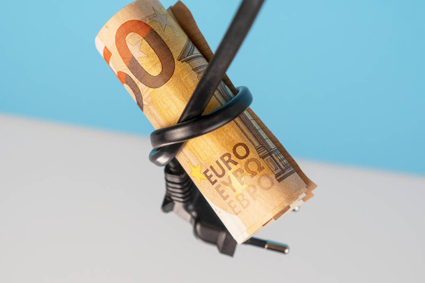 ユーロ銀行券は青の白の背景にプラグ付き電気ケーブルと結び目で結ばれました。緑の代替エネルギーと電力コスト削減コンセプト - 写真・画像