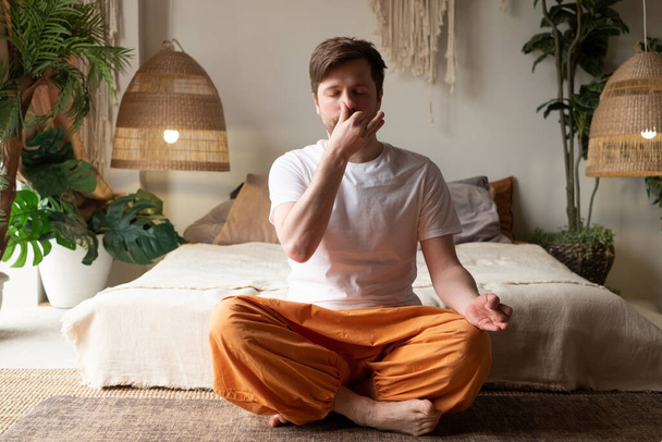 Caucasian mature man practicing yoga sitting, making Alternate Nostril Breathing - Foto, imagen