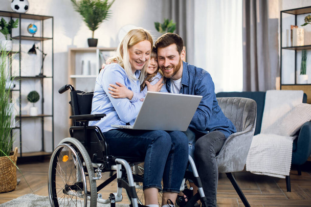 Man and child hugging woman in wheelchair with laptop - Foto, afbeelding