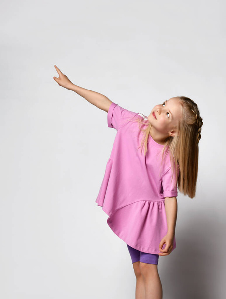 Happy cute little girl in dress smiling and pointing away - Foto, Imagen