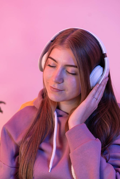 Het meisje luistert naar muziek in een koptelefoon met gesloten ogen. - Foto, afbeelding