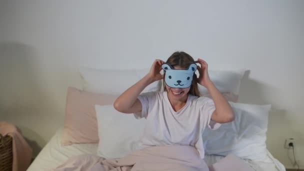 Happy sleepy young adult woman waking up lying in white bed - Footage, Video