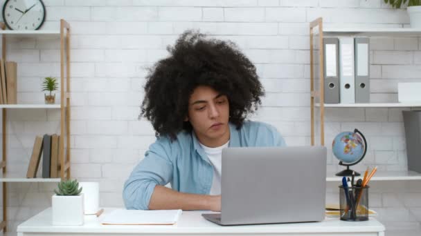 Frustrado estudiante chico mirando a portátil cansado de aprender en interiores - Imágenes, Vídeo