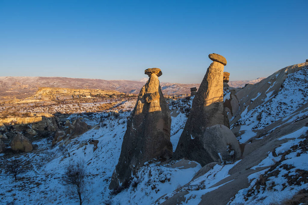 Három Graces vagy Uc Guzeller jéggel. Cappadocia tündér kéményei. Alakított kövek. Természetes sziklaüreg. Geológiai struktúrák. Ősi civilizáció. Urgup - Goreme régió. Nevsehir, Törökország. 2021. február - Fotó, kép