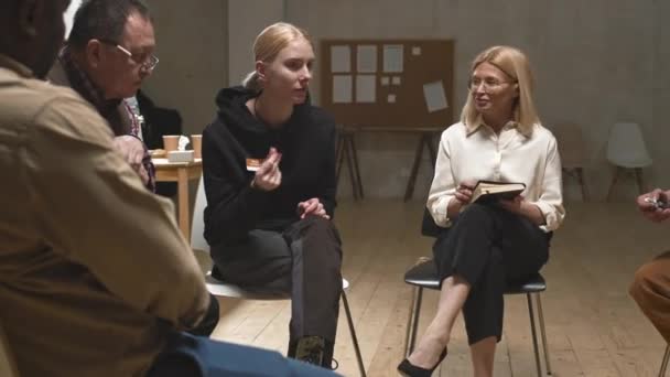 Середній знімок бунтівливої і проблемної молодої жінки в чорному светрі сидить на стільці на сесії групи підтримки психічного здоров'я з проханням про сигарету, говорячи про її проблеми з жіночим психологом
 - Кадри, відео