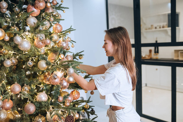 Mujer bastante atractiva decora el árbol de Navidad con bolas - Foto, imagen