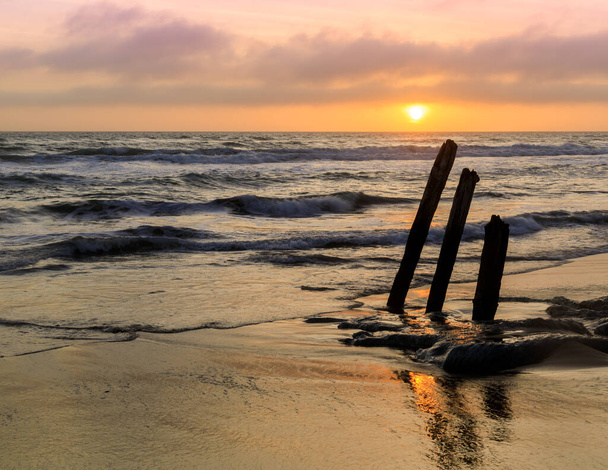 Sunset over ruined old pier pilings at Fort Funston Beach. San Francisco, California, USA. - Photo, Image