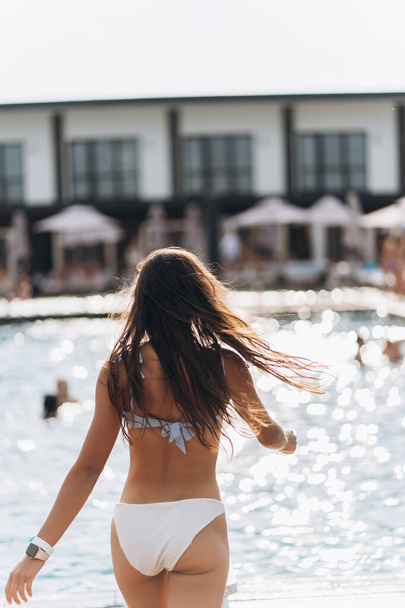 Молодая женщина на фоне бассейна в белом купальнике. - Фото, изображение