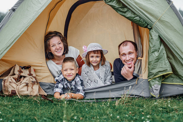 Family Parents and two children in camp tent. Happy Mother, father, son and daughter on Summer vacation. - Foto, imagen