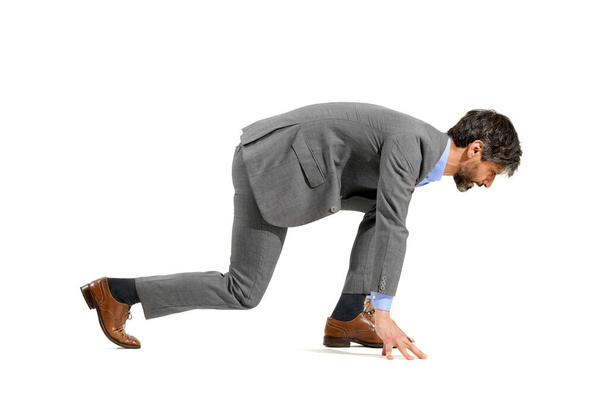 Stylish businessman in suit in the starter position for a race crouching forwards ready to run in a challenge, opportunity, ambition or competition concept isolated over a white studio background - Photo, Image