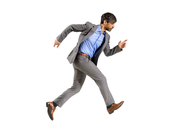 Hombre de negocios en un traje elegante caminando muy rápido con prisa con una expresión enfocada determinada caminando sobre un fondo blanco - Foto, Imagen