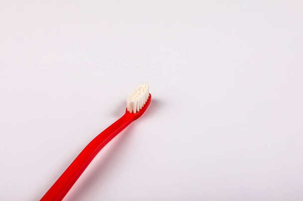 Red plastic toothbrush on a white background. Copy space - Zdjęcie, obraz