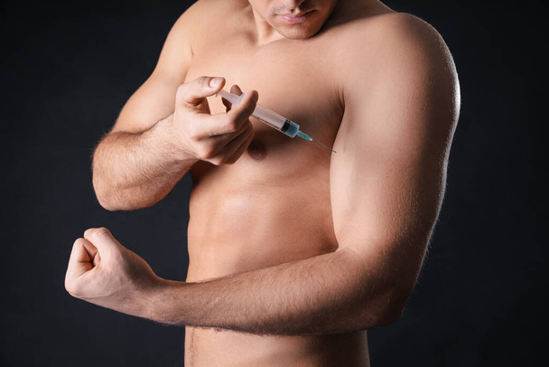 Athletic man injecting himself on black background, closeup. Doping concept - Foto, Imagem