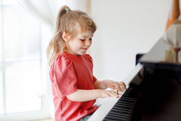 Gyönyörű kislány zongorázik a nappaliban. Aranyos óvodás gyerek szórakozás megtanulni játszani hangszeren. Korai zenei oktatás a gyermekek számára. - Fotó, kép