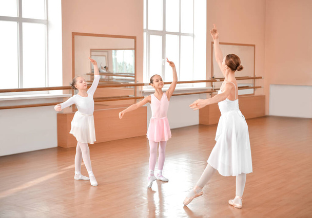 Маленькие балерины тренируются с тренером в танцевальной студии - Фото, изображение
