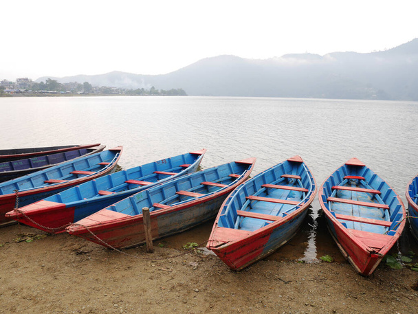 ネパール人と外国人旅行者のボートは、ネパールのガンダキ・プラデーシュ州のポカラでリラックスした訪問ツアーを漕ぐ - 写真・画像
