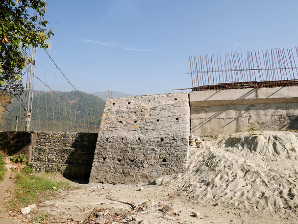 ナパリの人々のための建設現場は、ネパールのポカラにあるガンダキ・プラデーシュ州の田舎の丘の谷の村で石コンクリート灌漑貯水池ダムと修復メンテナンスフェワ道路を構築します - 写真・画像