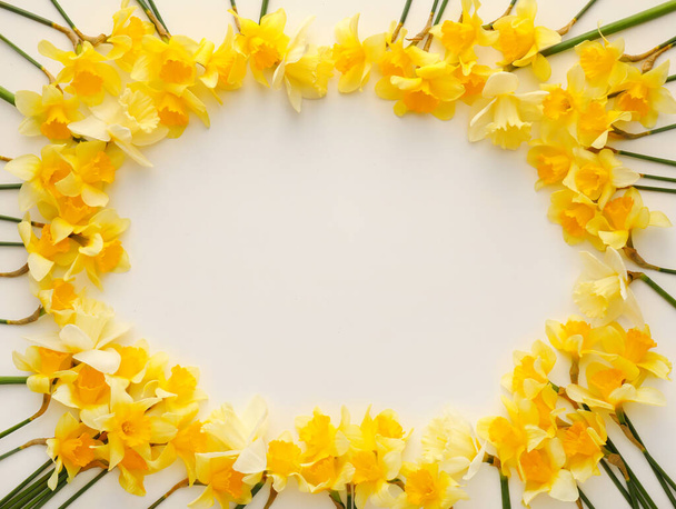 Frame made of beautiful daffodils on light background - Foto, afbeelding