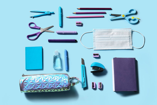 Pencil case with stationery and medical mask on color background - Photo, Image
