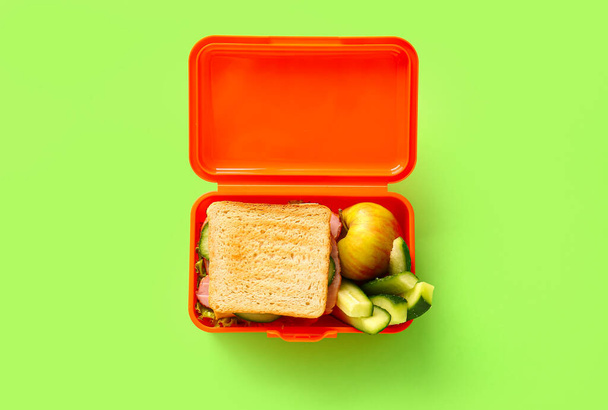 Caja de almuerzo con comida sabrosa sobre fondo de color - Foto, Imagen