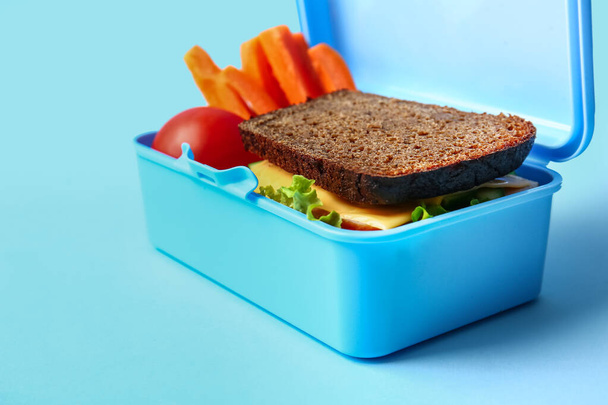 Scatola da pranzo con cibo gustoso su sfondo a colori - Foto, immagini