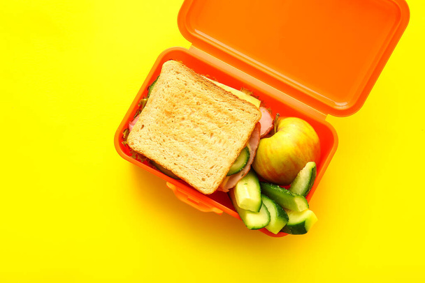 Caja de almuerzo con comida sabrosa sobre fondo de color - Foto, imagen