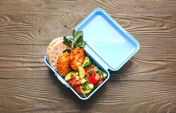 Oběd box s chutným jídlem na dřevěném pozadí - Fotografie, Obrázek