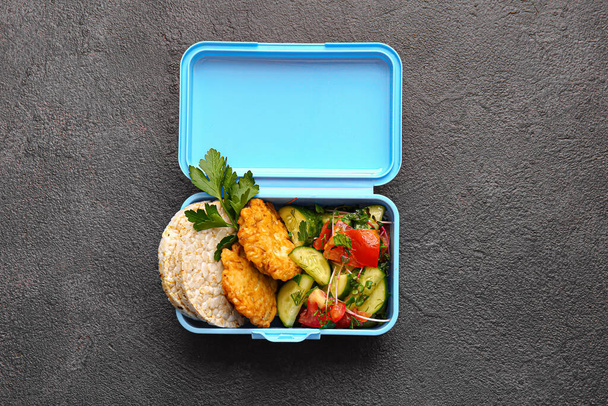 Γεύμα κουτί με νόστιμο φαγητό σε σκούρο φόντο - Φωτογραφία, εικόνα
