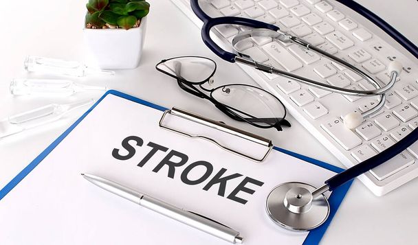 STROKE text on white paper on the white background. stethoscope ,glasses and keyboard - Photo, Image