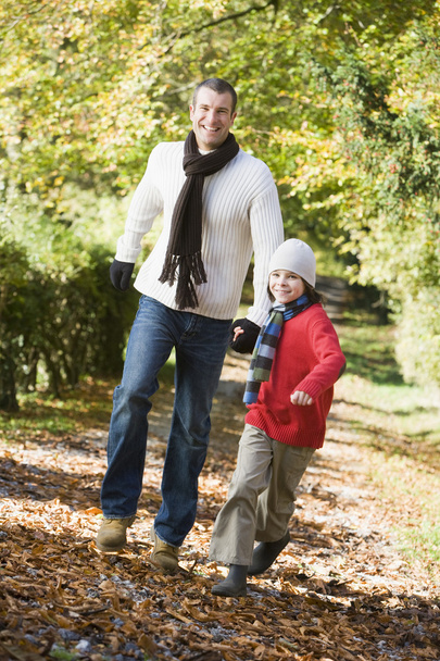 Father and son running along autumn path - Fotó, kép
