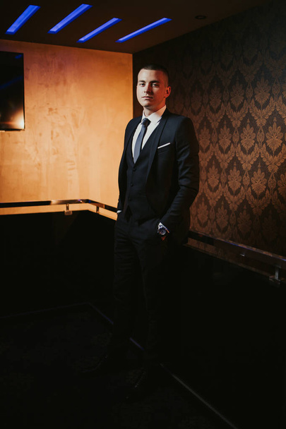 A vertical shot of a young caucasian man in a black suit - Photo, Image