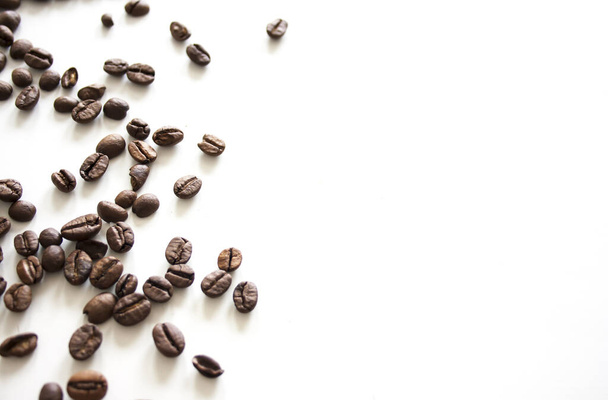 A top view of a heap of roasted coffee beans on a white surface - Foto, Bild
