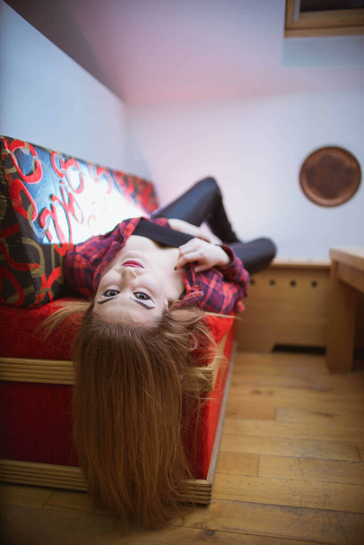 A young lady with makeup laying on the sofa and looking at the camera - Foto, Bild