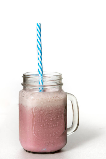 A closeup of the refreshing sweet and cold strawberry smoothie in a glass jar with a straw - Фото, зображення