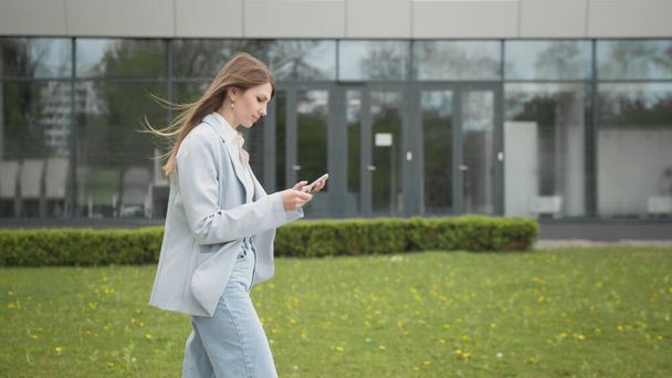 Ευτυχισμένη νεαρή γυναίκα που λαμβάνουν έκπτωση για ψώνια, ενώ τον έλεγχο κουτί e-mail, ενώ το περπάτημα στην αστική ρύθμιση κάτω δρόμο. Γυναίκα εισάγει αριθμό πιστωτικής κάρτας για online αγορές χρησιμοποιώντας το smartphone - Φωτογραφία, εικόνα