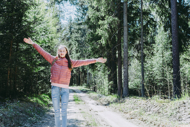 Young traveler girl arms outstretched raised enjoying the fresh air in the green summer spring forest.Sunny day,sun shine. - Photo, Image
