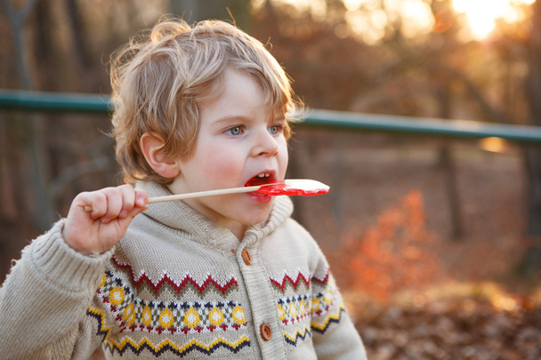 Retrato de hermoso niño de 2 años con grandes dulces, al aire libre
 - Foto, Imagen