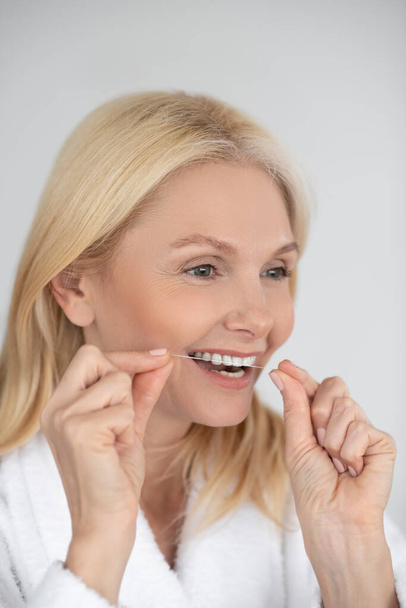 Dişlerini diş ipiyle fırçalayan bir kadının portresi. - Fotoğraf, Görsel