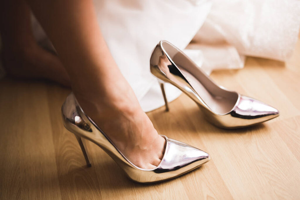 Bride puts on elegant and stylish bridal shoes on her tender feet - Photo, image